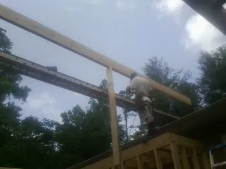 Carpenter setting a ridge beam over a new addition frame — Ice Dam Removal by Roofing Brothers in Waco